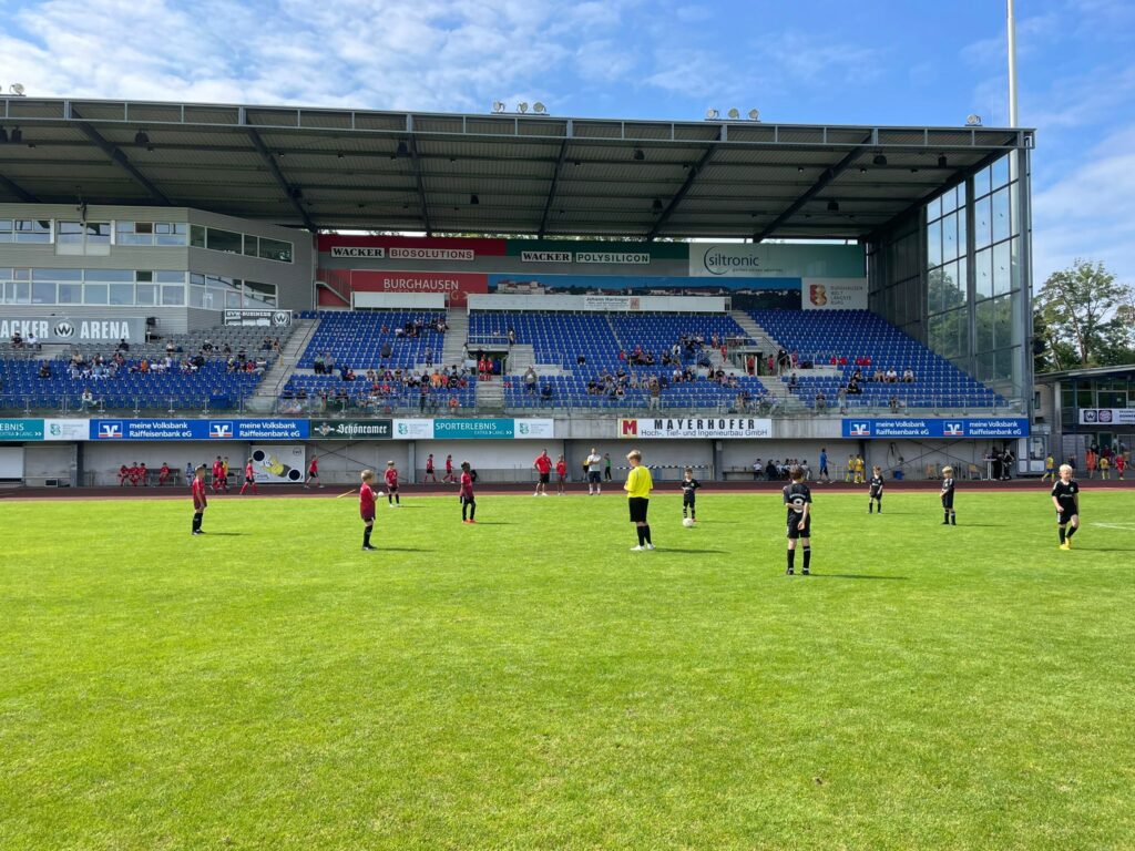 Jugendspieler kicken im Stadion des SV Wacker Burghausen vor der Haupttribüne